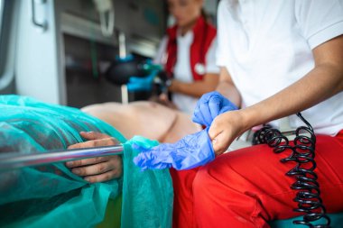 Afro-Amerikan Paramedikler, yaralı bir hastayla birlikte bir ambulans aracına mavi cerrahi lastik eldivenler takıyor. Acil tıp teknisyeni kurbanın hayati değerlerini kontrol ediyor..