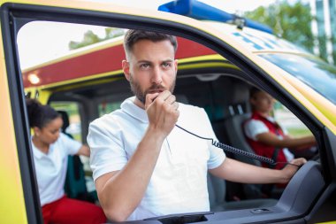 tarafından taşınabilir radyo konuşmak ve ambulans yakın duran yakışıklı erkek sağlık görevlisi