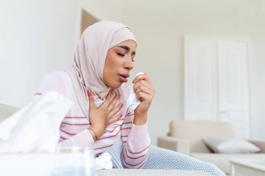 Arap kadın grip olmuş. Rhinitis hastası, tesettürlü bir kadının burnu akıyor. Kanepede yatan hasta bir kadın..