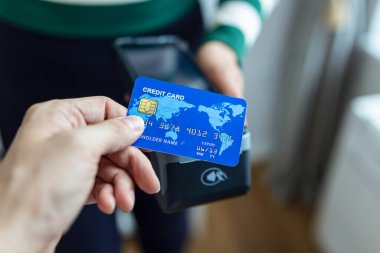 Contactless payment concept, female holding credit card near nfc technology on counter, client make transaction pay bill on terminal rfid cashier machine in restaurant store, close up view
