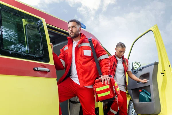 Paramedic nurse and emergency doctor at ambulance with kit. a paramedic, standing at the rear of an ambulance, by the open doors.