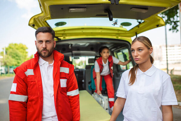 young paramedics moving ambulance stretcher from car. Paramedics in uniform taking stretcher out the ambulance car