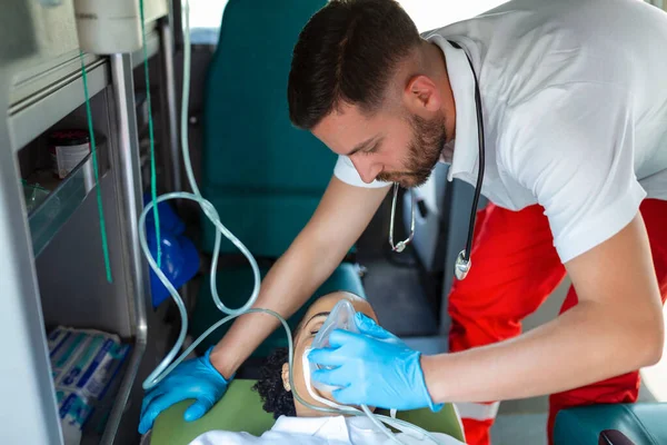 stock image paramedic healthcare emergency staff taking care of a lying down young woman patient on stretcher with medical ventilator system and bag-valve masks inside an medical service ambulance car.