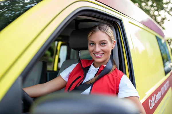 Ambulance staff members in her ambulance. She is wearing ambulance uniform of paramedics. She is sitting in the ambulance ready to go to a call