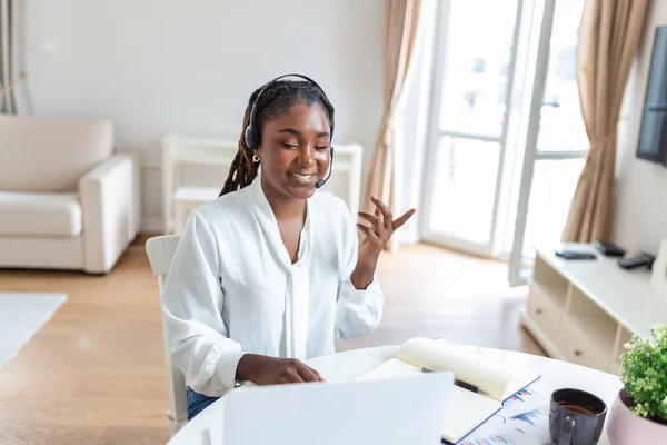 African-american elegant female entrepreneur discussing while having a conference call Portrait of confident ethnicity female employee looking at laptop camera talking on video call in the home office