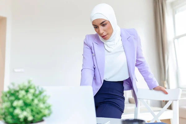 Muslim woman working with computer at home. Muslim woman working with computer in the room , writing paper. Confidence pretty muslim woman Business and finance concepts.