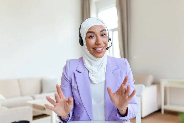 Businesswoman in hijab having a video chat on laptop . Female sitting at cafe and making video call using earphones and laptop computer.