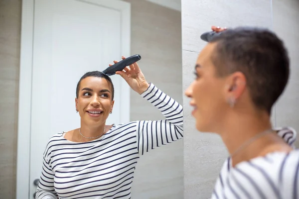 Saç Kesme Makinesi Kullanan Kısa Saçlı Bir Kadının Ayna Yansıması — Stok fotoğraf