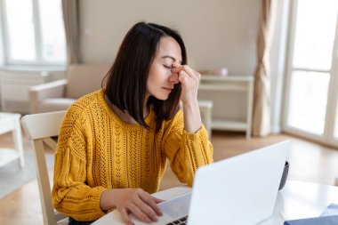 Ev bilgisayarının önünde çalışan hayal kırıklığına uğramış bir kadın kronik baş ağrısı çekiyor, internetten tedavi görüyor, tıbbi konsültasyon için randevu alıyor, elektromanyetik radyasyon alıyor, hastalık maaşı alıyor.