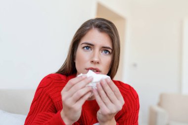 Hasta, çaresiz kadın grip olmuş. Rhinitis, soğuk, hastalık, alerji konsepti. Güzel hasta bir kadının burnu akıyor, burnu mendille sürtüyor. Hapşıran kadın. Esmer mendilin içinde hapşırıyor.