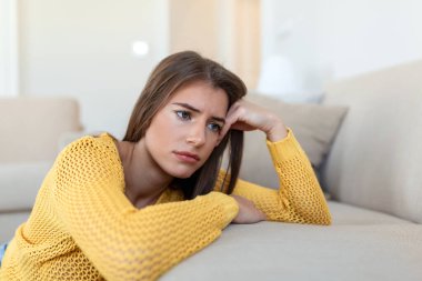 İşle ya da ilişkilerle ilgili sorunları olan üzgün bir kadın, koltukta oturuyor, yüzü örtülü, umutsuzluk ve endişe hissediyor, yalnızlık çekiyor, psikolojik sorunlar yaşıyor.