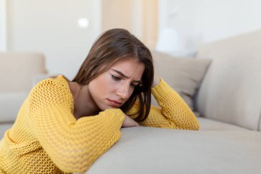 İşle ya da ilişkilerle ilgili sorunları olan üzgün bir kadın, koltukta oturuyor, yüzü örtülü, umutsuzluk ve endişe hissediyor, yalnızlık çekiyor, psikolojik sorunlar yaşıyor.