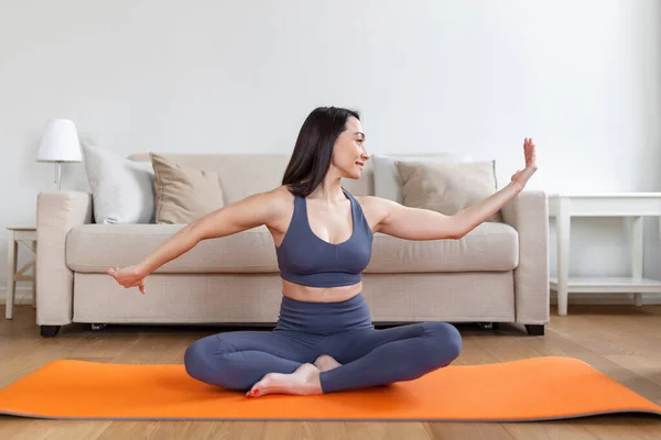 Asian woman exercising at home, stretching. Time for yoga. Attractive and healthy young woman doing exercises while resting at home. Young woman exercising at home, interior