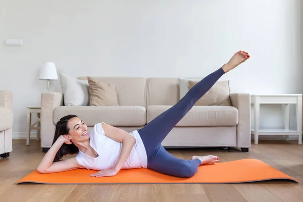 Asian woman exercising at home, stretching. Time for yoga. Attractive and healthy young woman doing exercises while resting at home. Young woman exercising at home, interior
