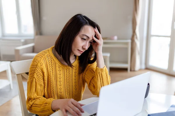 Asian woman concerned thinking about online problem.Frustrated worried middle aged female suffering from memory loss, having a headache.