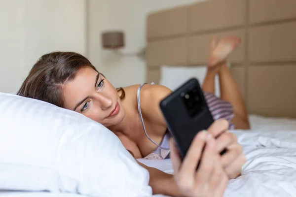 Donna Sorridente Guardando Telefono Cellulare Mentre Giaceva Sul Letto Bianco — Foto Stock