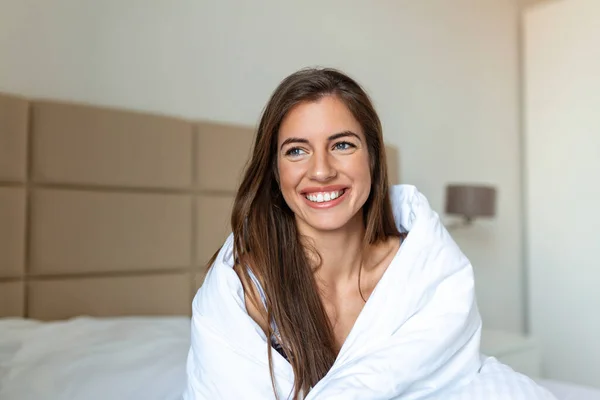 Woman wrapped in a blanket after wake up, entering a day happy and relaxed after good night sleep. Sweet dreams, good morning, new day, weekend, holidays concept