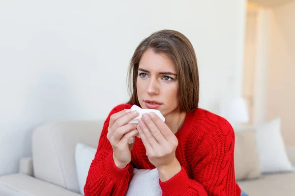 Sick desperate woman has flu. Rhinitis, cold, sickness, allergy concept. Pretty sick woman has runnning nose, rubs nose with handkerchief. Sneezing female. Brunette sneezing in a tissue