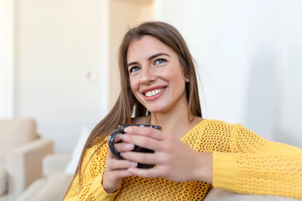 Closeup view of young woman with cup of hot drink at home, blank space. People, drinks and leisure concept - happy young woman with cup of tea or coffee at home