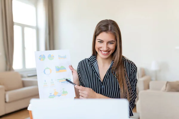 Focused business woman presenting charts and graphs on video call online. Young business woman having conference call with client on laptop. Young woman explaining how business work
