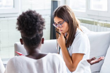 Ofiste çalışan ve hastayı dinleyen doktor, semptomlarını, sağlık hizmetleri ve yardım konseptini açıklıyor..