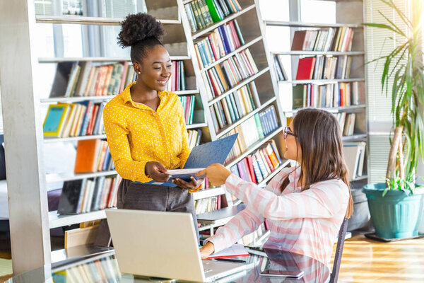 African American business woman holding papers and smiling.Young team of colleorkers making great business discussion in modern coworking office e.Teamwork people concept.