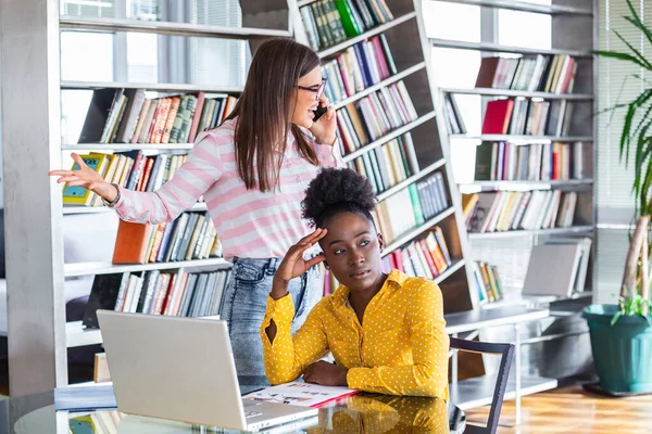 Mobbing at work, bad job relations concept. Angry mad bossy businesswoman talking on phone sitting working at desk full off documents in binders.