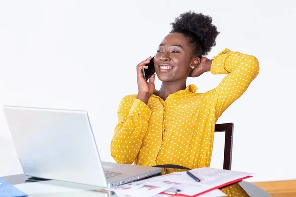 Trendy business woman talking on phone, home-office. African American woman at training seminar, female business leader going true paperwork at her office