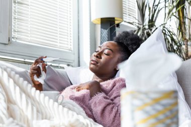Sickness, seasonal virus problem concept. Woman being sick having flu lying on bed looking at temperature on thermometer. Sick woman lying in bed with high fever. Cold flu coronavirus, covid19