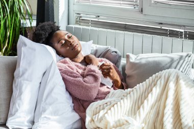 Hasta Kadın Üşüttü. Dokuların içine hapşırmak. Baş ağrısı. Virüs. İlaçlar. Burnunu mendile sümküren soğuk algınlığına yakalanmış genç bir kadın. Kanepede oturan, başı ağrıyan hasta kadın.