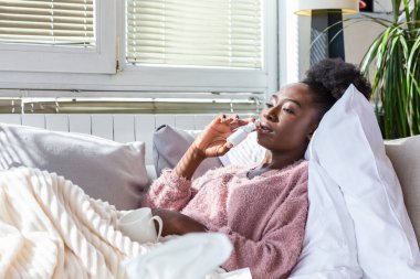 Kadın grip olmuş ve kendine yardım etmek için burun spreyi kullanıyor. Burun spreyi kullanan bir kadın. Soğuk algınlığına iyi gelir. Burun kıvrımları akıyor. Kadın burun spreyi sıkar.