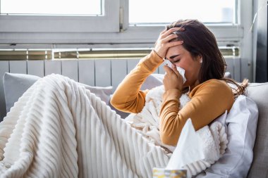 Soğuk ve soğuk algınlığı. Hasta olan, hasta hisseden ve kağıt mendile hapşıran bir kadının portresi. Battaniye Burunlu Güzel Sağlıksız Kız 'a yakın çekim. Sağlık Hizmetleri Konsepti.