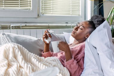 Hasta, çaresiz kadın grip olmuş. Rhinitis, soğuk, hastalık, alerji konsepti. Güzel hasta bir kadının burnu akıyor, burnu mendille sürtüyor. Mendilin içinde hapşıran Afrikalı Amerikalı kadın