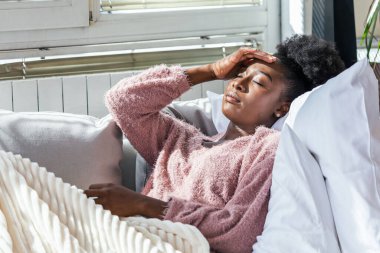 Hasta kadın. Flu. kadın üşüttü. Dokuların içine hapşırmak. Baş ağrısı. Virüs. İlaçlar. Burnunu mendile sümküren soğuk algınlığına yakalanmış genç bir kadın. Kanepede oturan, başı ağrıyan hasta kadın.