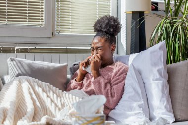 Battaniyenin altında oturan hasta Afrikalı Amerikalı kadın. Yatağında battaniyeyle yatan hasta kadın mevsimsel enfeksiyonlar, grip, alerji....