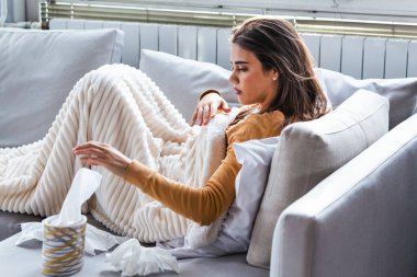 Soğuk ve grip. Hasta kadın portresi üşütmüş, hasta ve kağıt mendil hapşırma. Güzel sağlıksız kız closeup burun silmekten battaniyeye örtülü. Sağlık kavramı. Yüksek çözünürlük