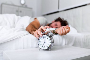 Daha uzun uyu. Sağlık hizmeti konsepti. Uykunun aşamaları. Alarm çaldığı için mutsuz bir adam uyandı. Uyuyor olsan da hiç uyumamış gibi hissedebilirsin..