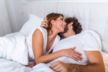 Yatakta öpüşen güzel bir çift. Yatakta birlikte uzanan güzel genç bir çift. Aşık romantik genç bir çift yatakta yatıyor. Yatakta gülümseyen güzel çift.