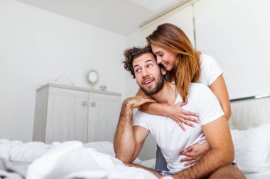 Yatakta partnerini kucaklayan bir kadın, yatakta duygularını ve sevgisini gösteren mutlu bir çift. Yatakta öpüşen güzel bir çift. Güzel genç bir çift yatakta birlikte yatıyor..