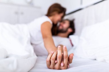 Romantik çift yatakta şehvetli ön sevişmenin tadını çıkarıyor. Ellere odaklan, erkek ve kadın. Yatakta birlikte yatan mutlu, şehvetli genç çift. Güzel bir çift yatakta öpüşüyor..