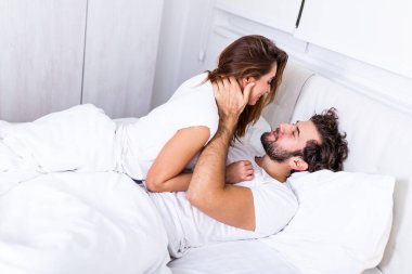 Yatakta öpüşen güzel bir çift. Yatakta birlikte uzanan güzel genç bir çift. Aşık romantik genç bir çift yatakta yatıyor. Yatakta gülümseyen güzel çift.