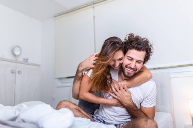 Evdeki güzel genç çift. Sarılmak, öpüşmek ve birlikte vakit geçirmekten zevk almak. Yatak odasındaki tutkulu güzel çift ön sevişmenin tadını çıkarıyor.