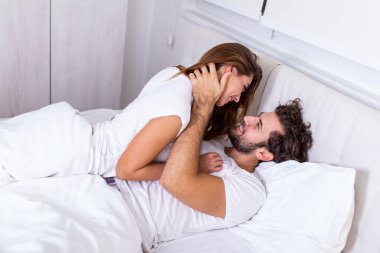 Yatakta öpüşen güzel bir çift. Yatakta birlikte uzanan güzel genç bir çift. Aşık romantik genç bir çift yatakta yatıyor. Yatakta gülümseyen güzel çift.