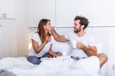 Yatakta romantik bir kahvaltı hazırladı. Kadın çok mutluydu. Genç ve güzel bir çift yatakta kahvaltı edip kahve içiyordu. Genç çift yatakta romantik bir kahvaltı yapıyor..