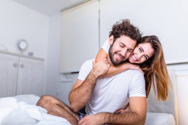 Evdeki güzel genç çift. Sarılmak, öpüşmek ve birlikte vakit geçirmekten zevk almak. Yatak odasındaki tutkulu güzel çift ön sevişmenin tadını çıkarıyor.
