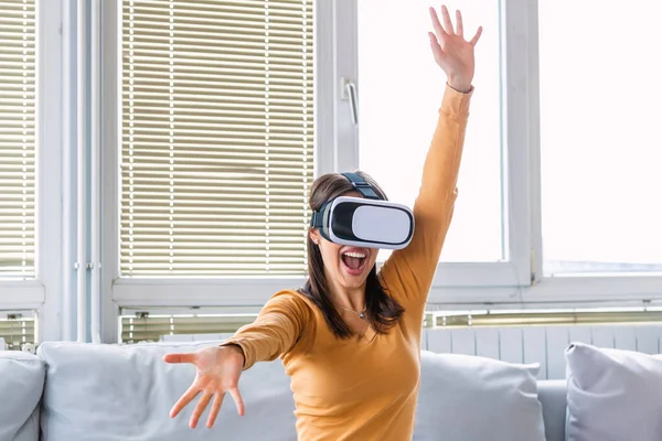 O kadar gerçek ki! Çekici bir kadın evde halıda otururken VR kulaklığını ayarlıyor ve gülümsüyor. VR gözlükleri. 360 derece. Sanal gerçeklik kulaklığı. VR oyunu. Sanal gerçeklik gözlüğü takıyor..