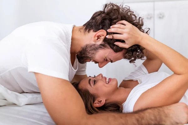 有爱心的年轻貌美的夫妻在家里的卧室里共度一段浪漫的时光 一对快乐的年轻夫妇在家里的卧室里躺在床上 一边拥抱一边笑 — 图库照片