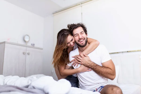 女人在床上拥抱她的伴侣 快乐的夫妻在床上表现出感情和爱心 美丽的恋人在床上接吻 那对年轻貌美的夫妇躺在床上 — 图库照片