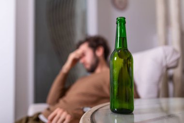 Alkol şişesinin arkasında içki içen isimsiz alkoliğin silueti. Alkol alışkanlıklarıyla kavga eden bir adam, evde kanepede oturup içki içen bir adam.