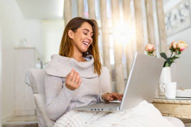 Defterde uzun saçlı güzel bir bayan evdeki kanepeye oturur - pazartesi siber satış için benzin dükkanlarını kontrol eder- alternatif ofis için teknoloji kadını konsepti